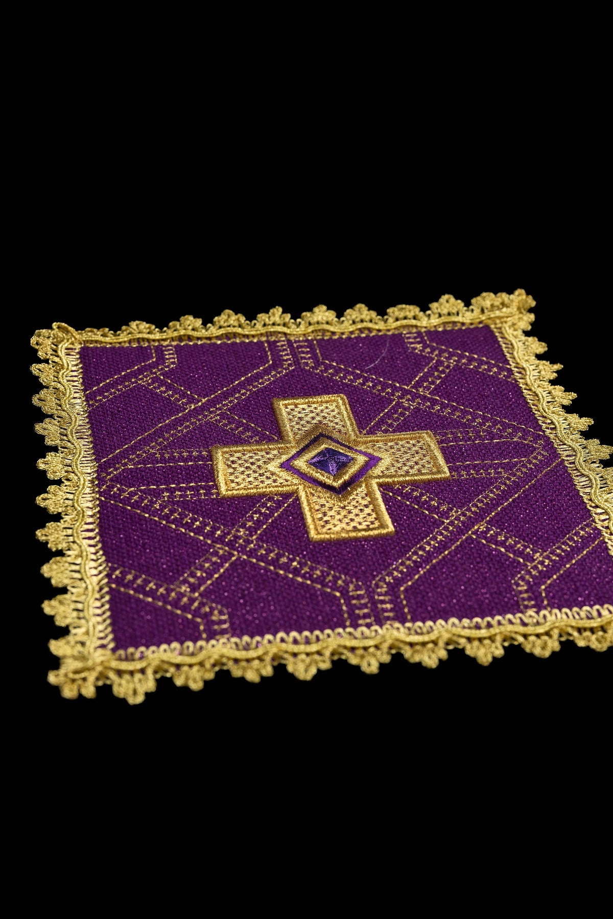 Pale de calice violette, vue rapprochée, avec croix brodée et galon doré