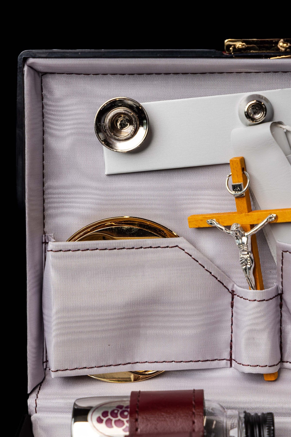 Valise liturgique, gros plan sur le compartiment doré et le crucifix en bois