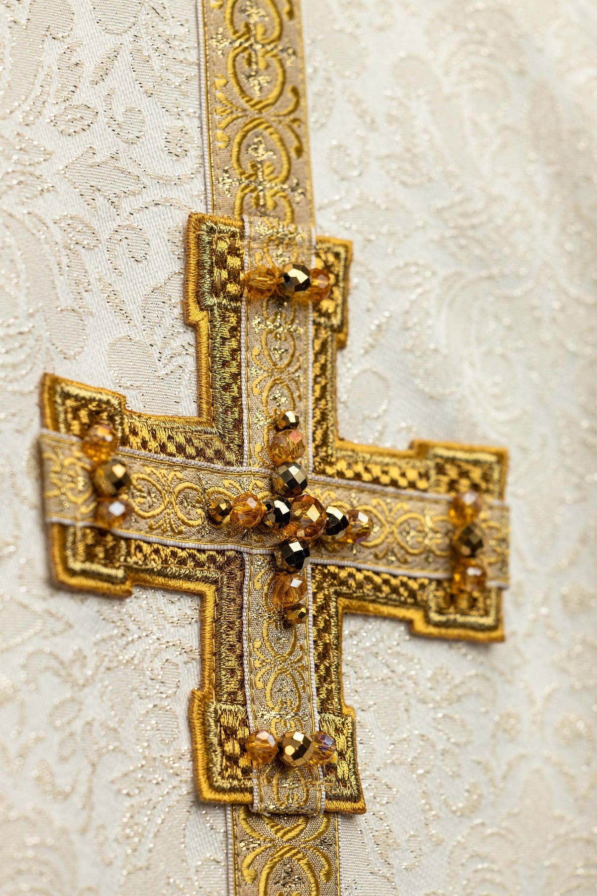 Chasuble faite main ivoire, gros plan sur la croix dorée ornée de pierres naturelles