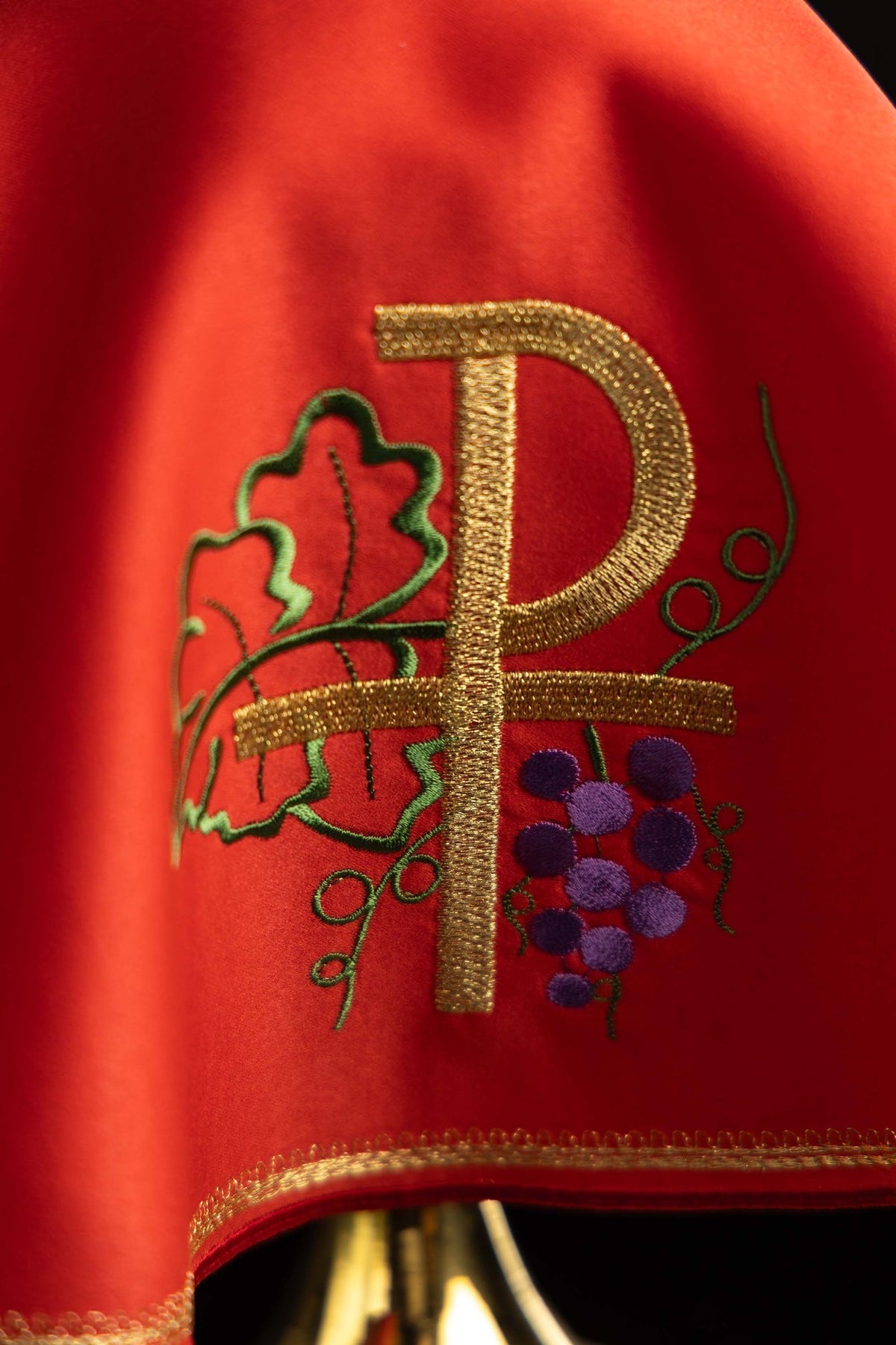 Voile de ciboire rouge, gros plan sur la broderie PAX dorée avec feuilles et grappes de raisin