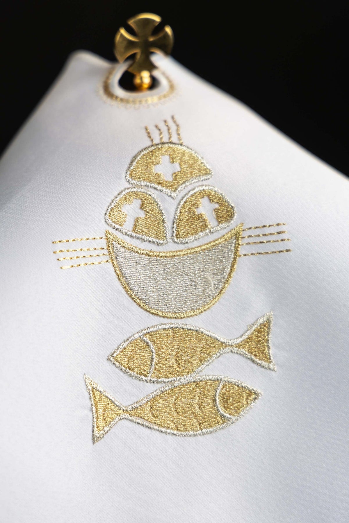 Voile de ciboire blanc, gros plan sur la broderie dorée du pain et des poissons