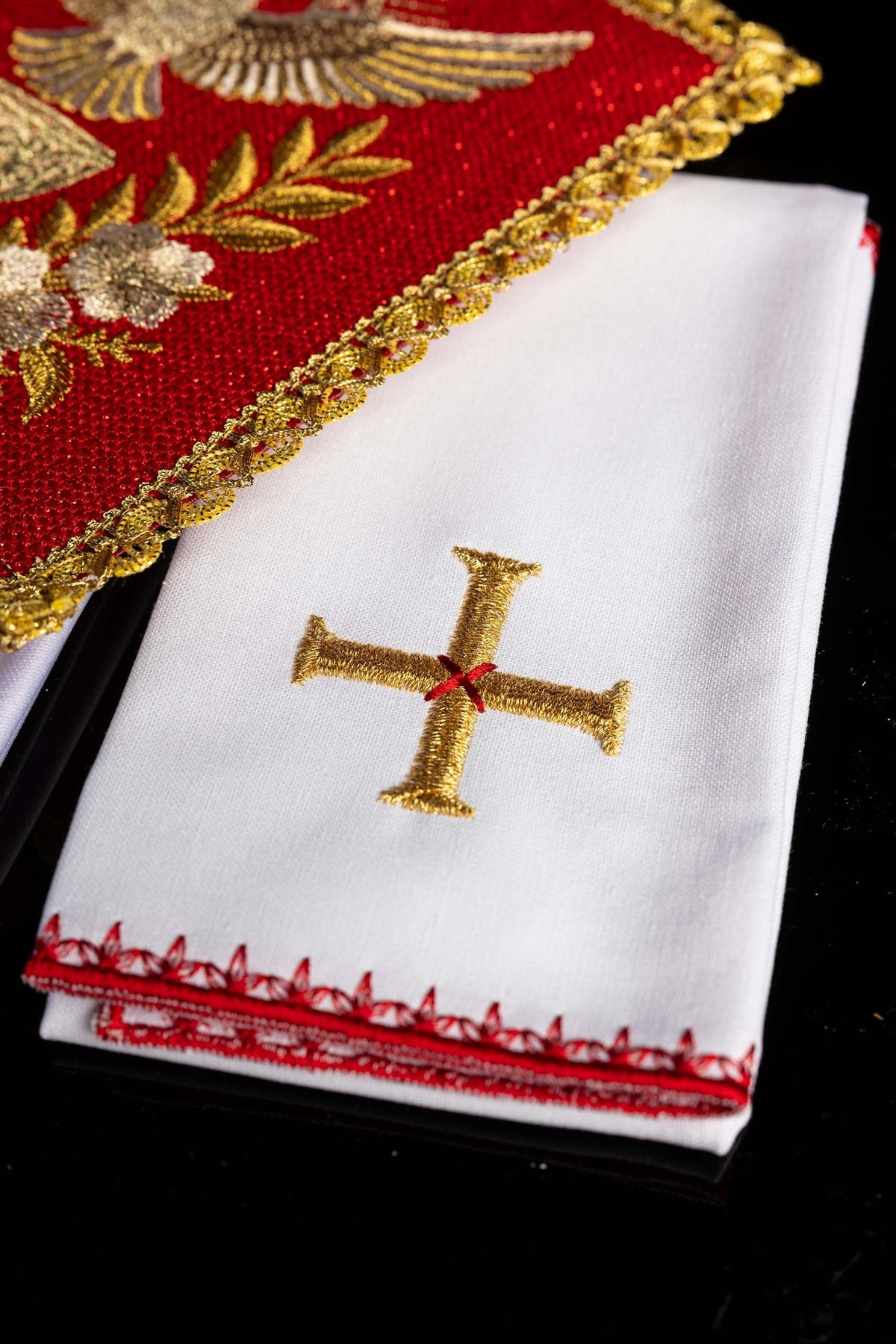 Linge de calice blanc, détail de la croix dorée et de la bordure rouge brodée
