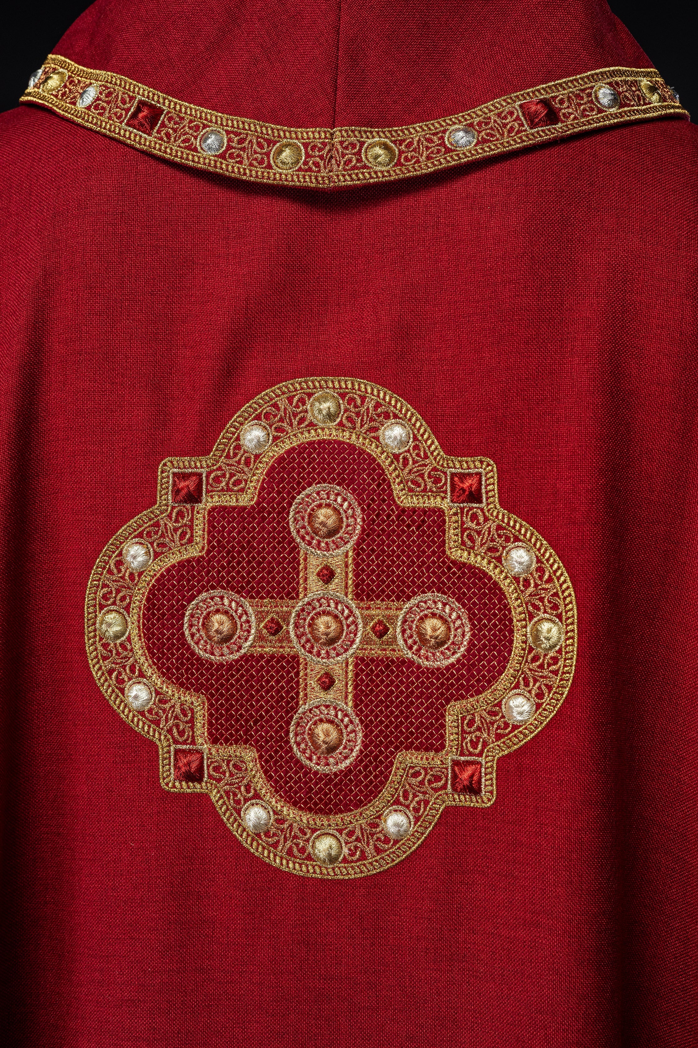 Chasuble en rouge avec passepoil brodé sur le col et autour de la broderie de la croix