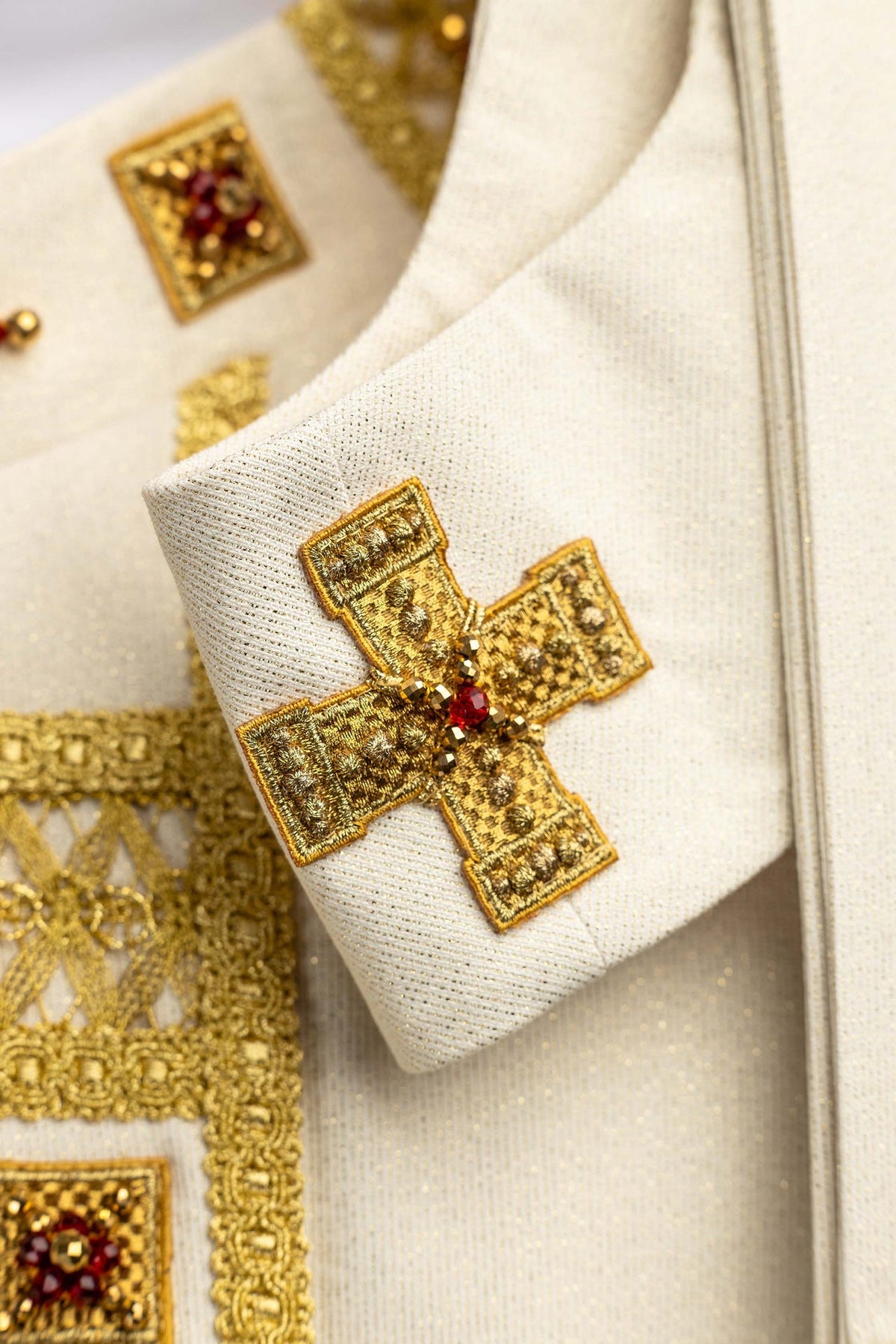 Chasuble faite à la main avec des pierres naturelles, gros plan sur la croix dorée et les pierres rouges