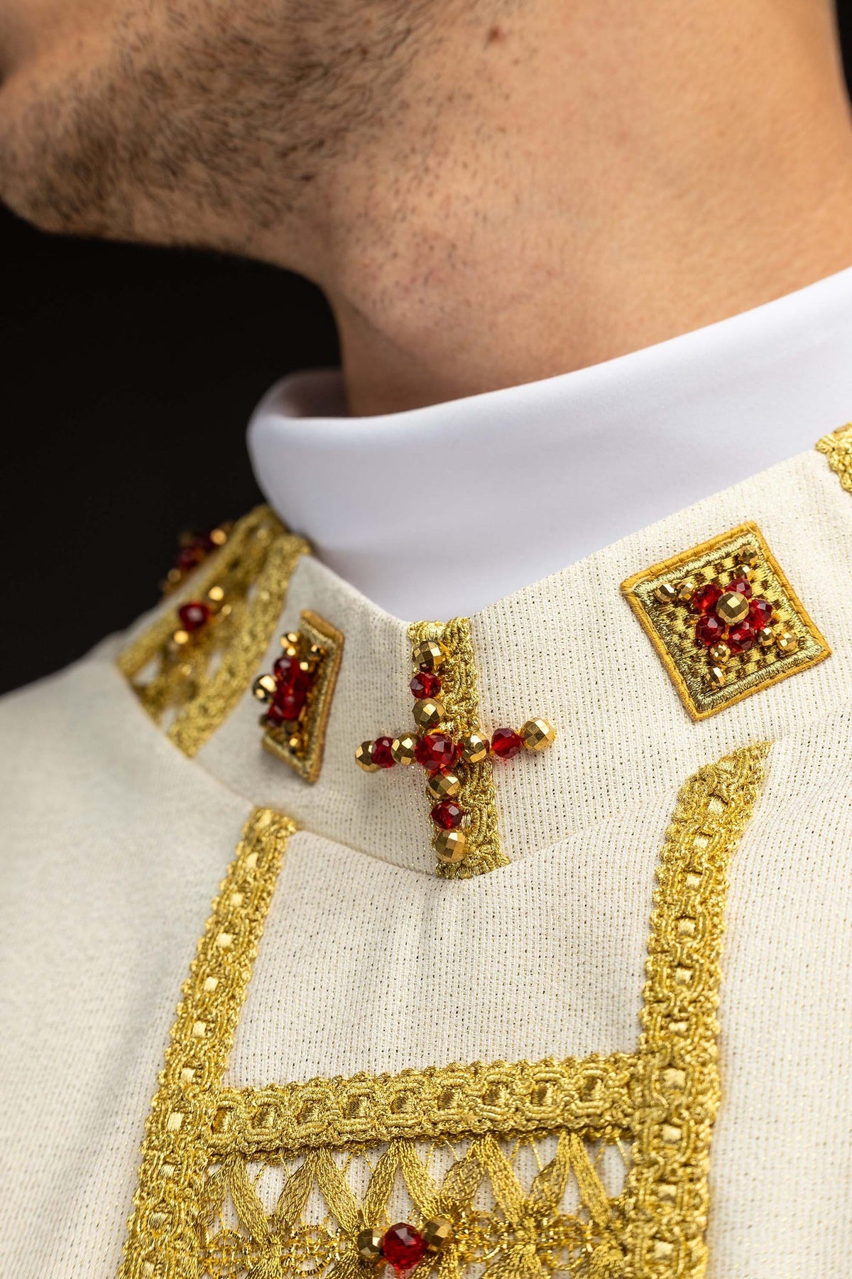 Chasuble, gros plan sur le col orné de croix et de pierres rouges