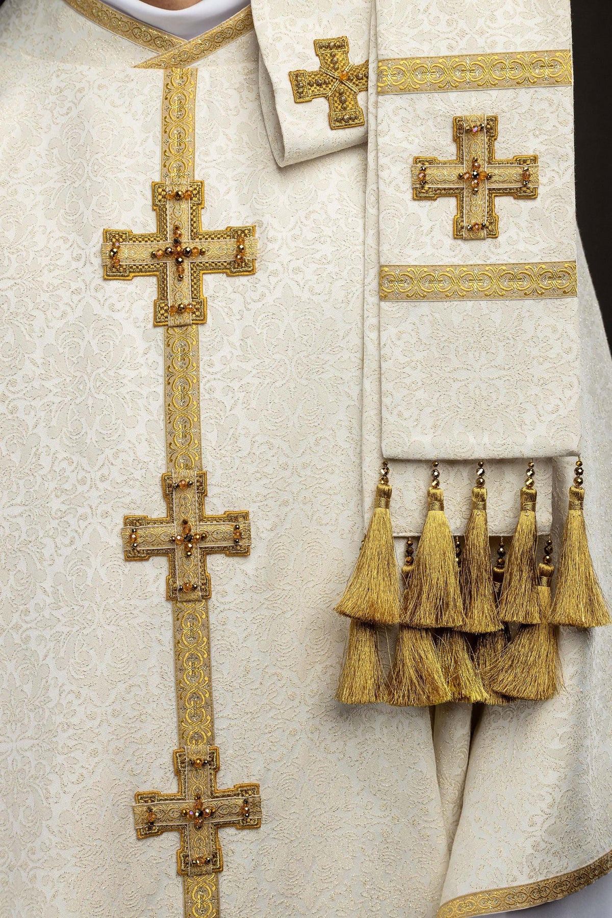 Chasuble ivoire portée, gros plan sur la manche bordée de galon doré