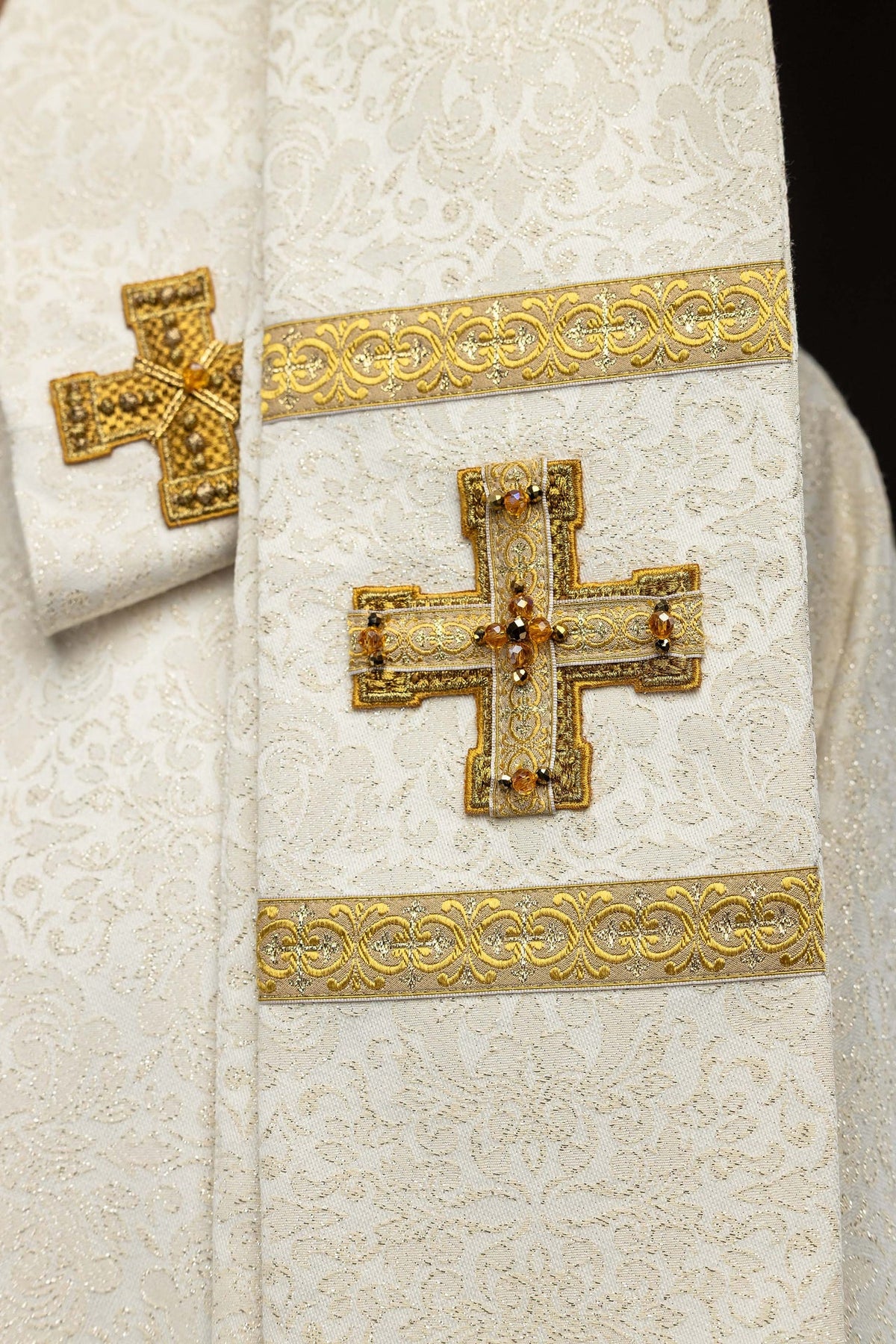 Chasuble ivoire avec croix dorées, pompons et galons décoratifs visibles