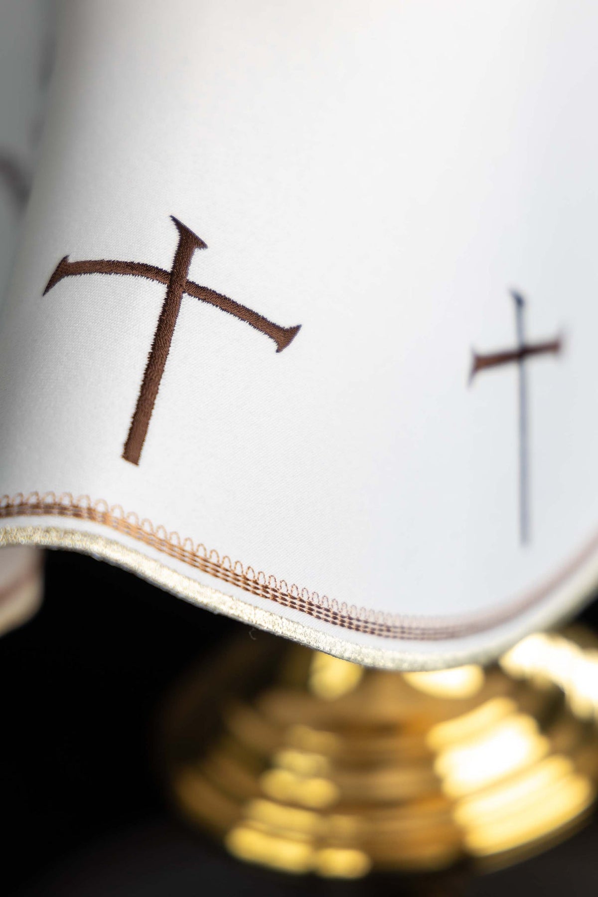 Voile de ciboire blanc, détail des croix brunes et de la bordure brodée